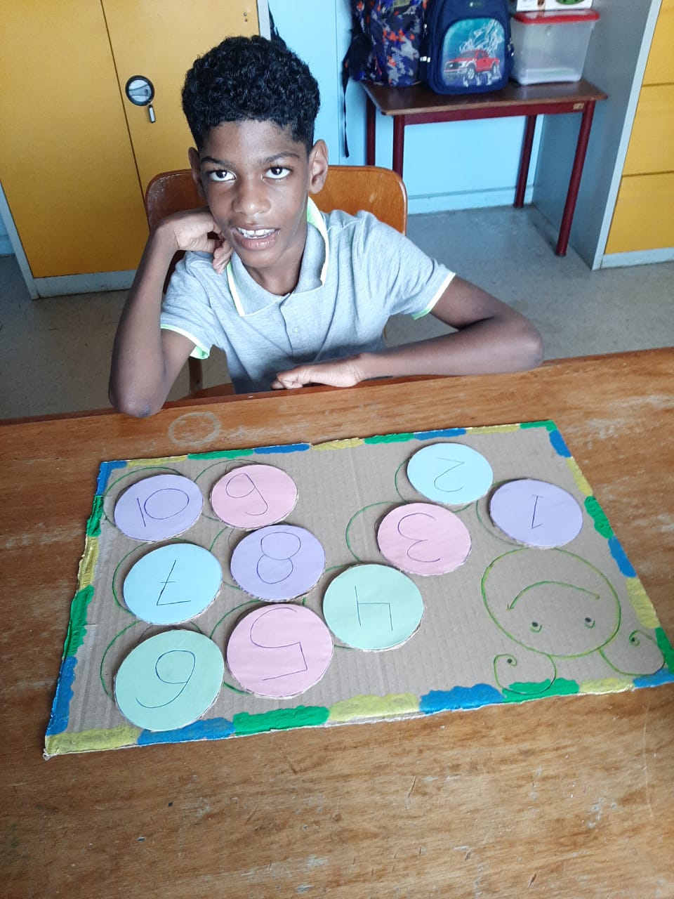 A young child plays a game that is hand drawn on cardboard.