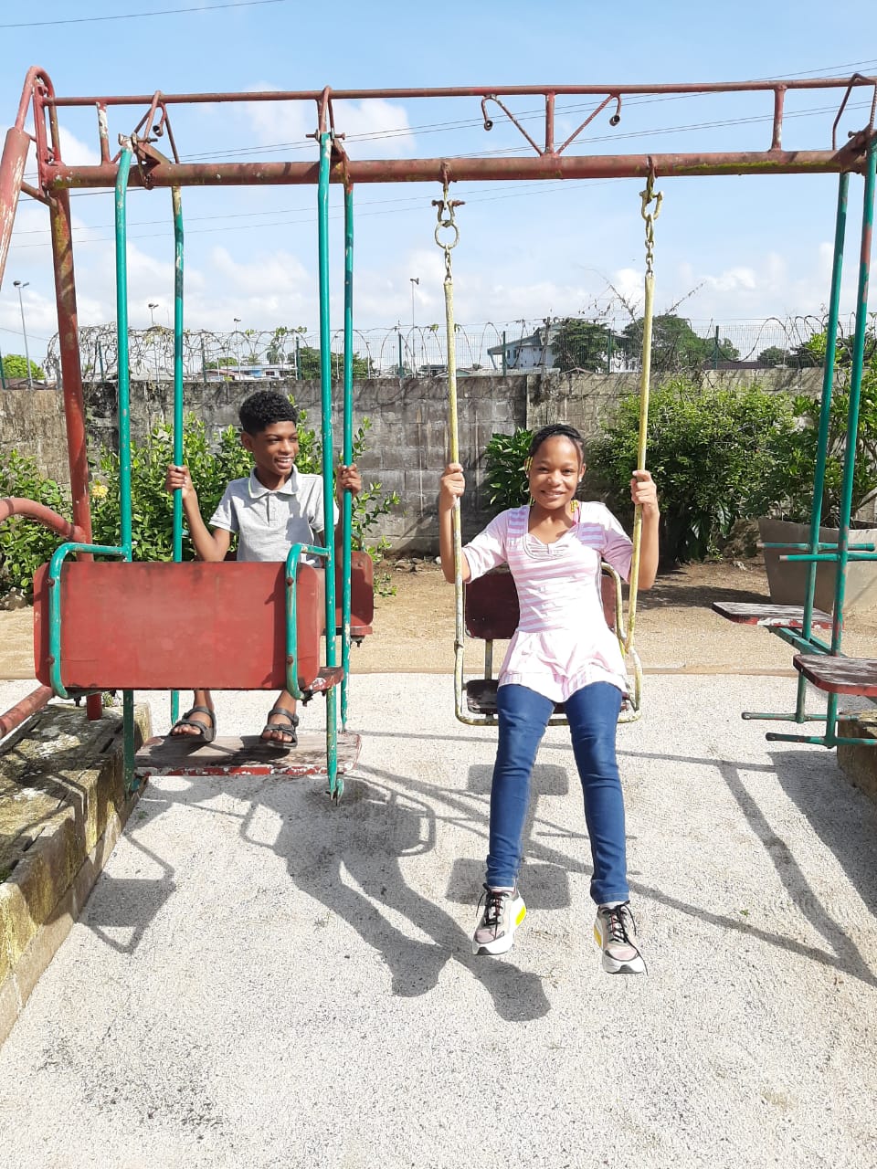 Two children smile on the swing set at StigesU.